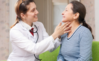 A female doctor examines a female patient's upper neck for endocrine glands.